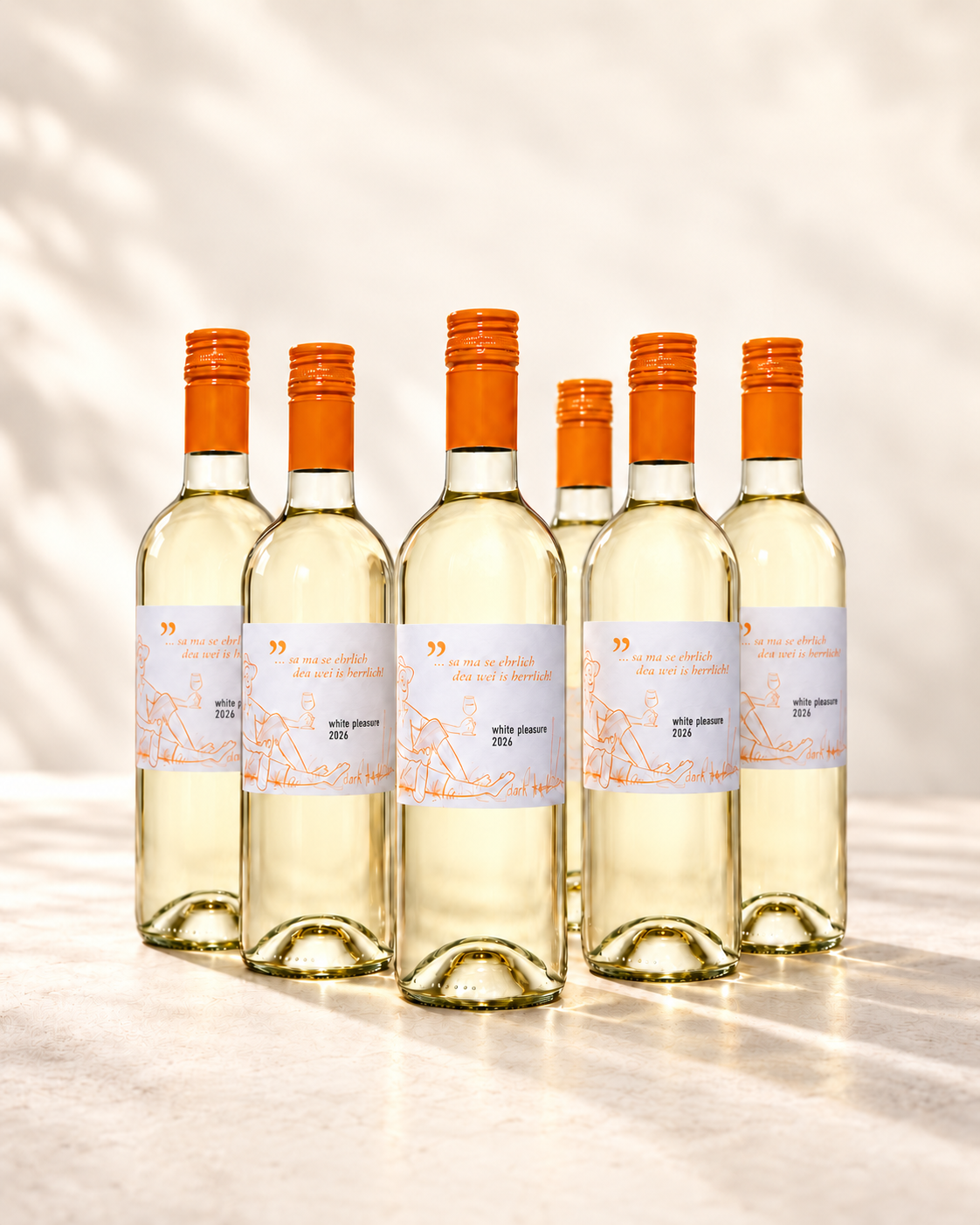 Sechs Flaschen white pleasure 2026 mit orangefarbenen Verschlüssen vor hellem Hintergrund